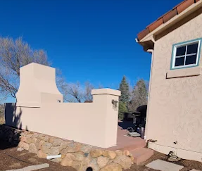 Stucco courtyard with outdoor fireplace and stone base