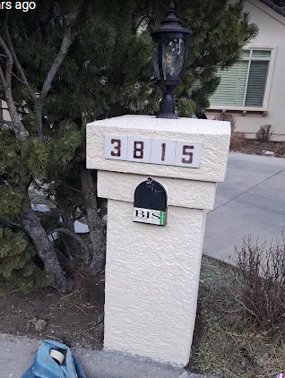 White stucco mailbox pillar with address